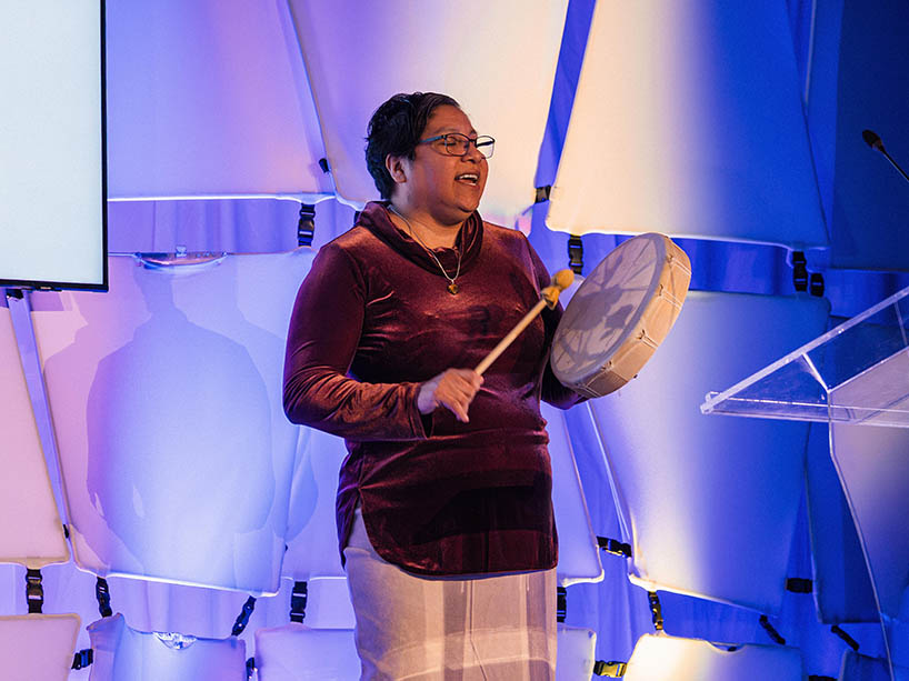 Amy Desjarlais sings and plays a hand drum.