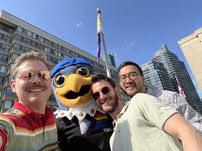 TMU’s mascot, Frankie B. Bold, Ryan Kerr, Michael Turco and Dan Cantiller take a selfie with the Pride flag.