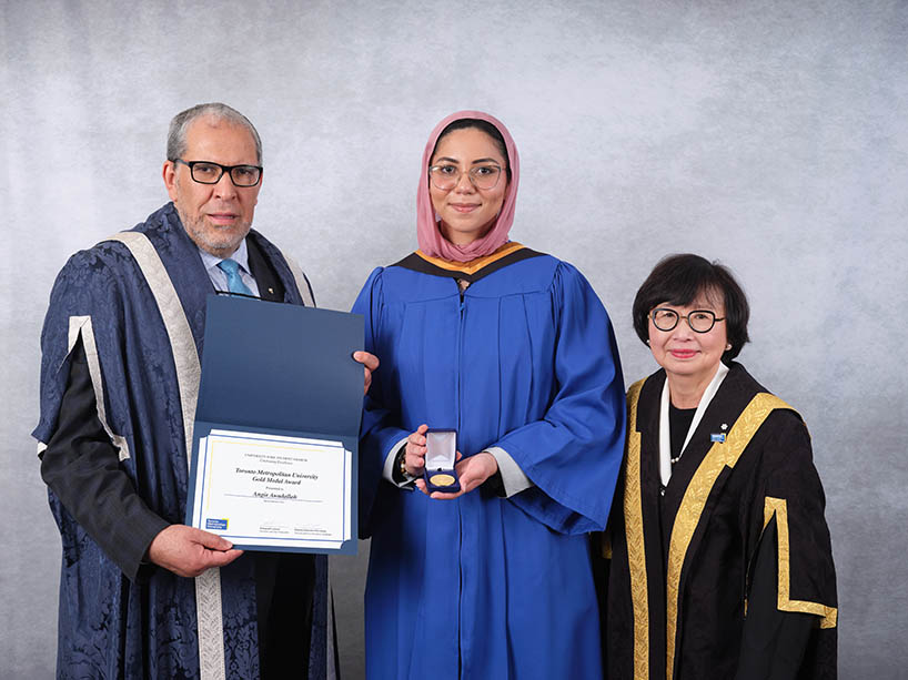 Three people wearing academic regalia pose for a photo after a Toronto Metropolitan University convocation ceremony.