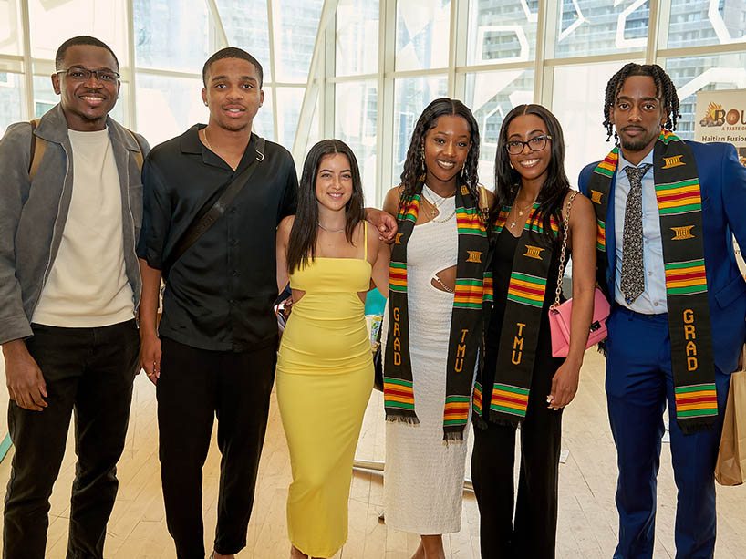 Amanuel Mulualem Dinberu with two fellow Black graduates wearing Kente stoles and three friends.