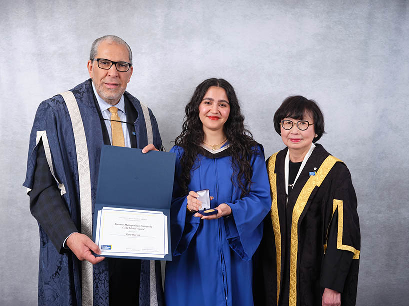 A man holding a certificate and a woman holding a gold medal pose for a photo at a Toronto Metropolitan University convocation ceremony.