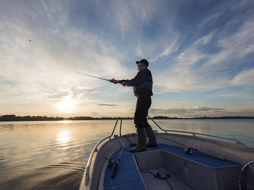 A man casts a fishing line off a boat