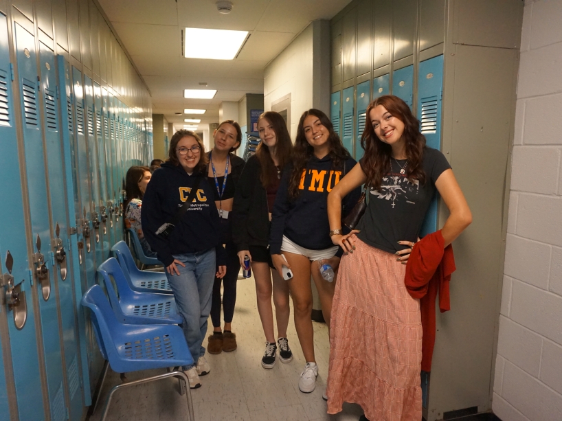 A group of young women pose for a photo in a school hallway.