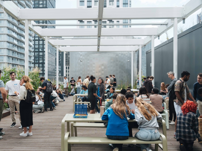 Students sit and stand in small groups while hanging out on the patio area of one of TMU’s rooftop gardens.