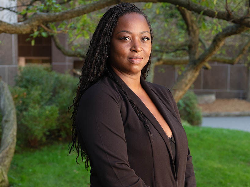 Victoria Akinola stands outside on the grass looking at the camera.