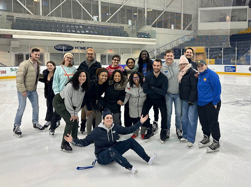 A group of people posing for a photo on ice at an ice rink. 