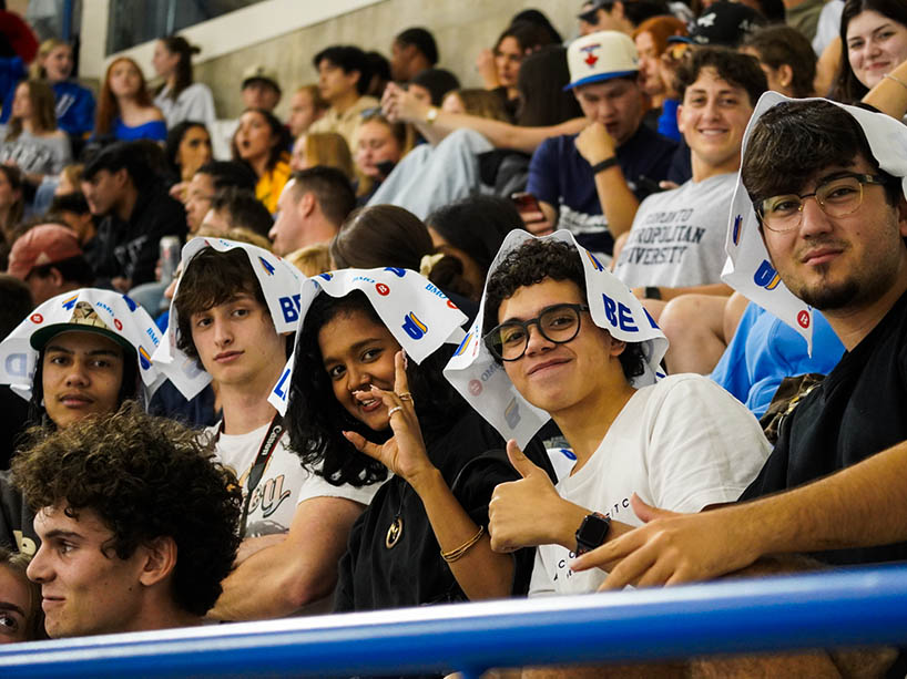 A grop of people smiling in the stands. 