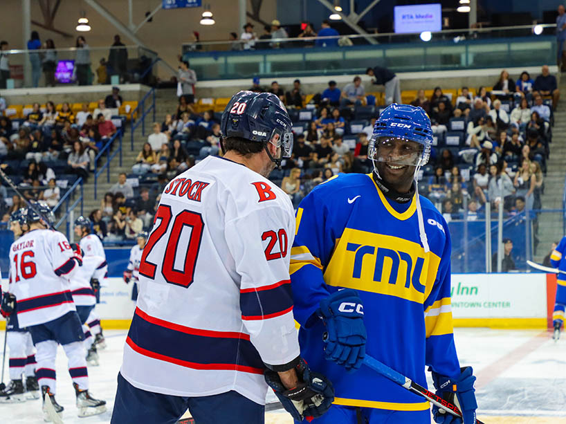 Two hockey players from opposing teams on the ice together. 