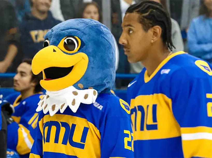 TMU’s Frankie the falcon mascot in a blue and yellow jersey, surrounded by TMU hockey players.