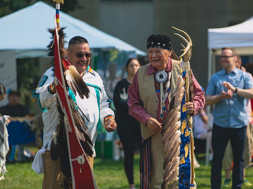 Two flag carriers smile and laugh together as they lead in other dancers.