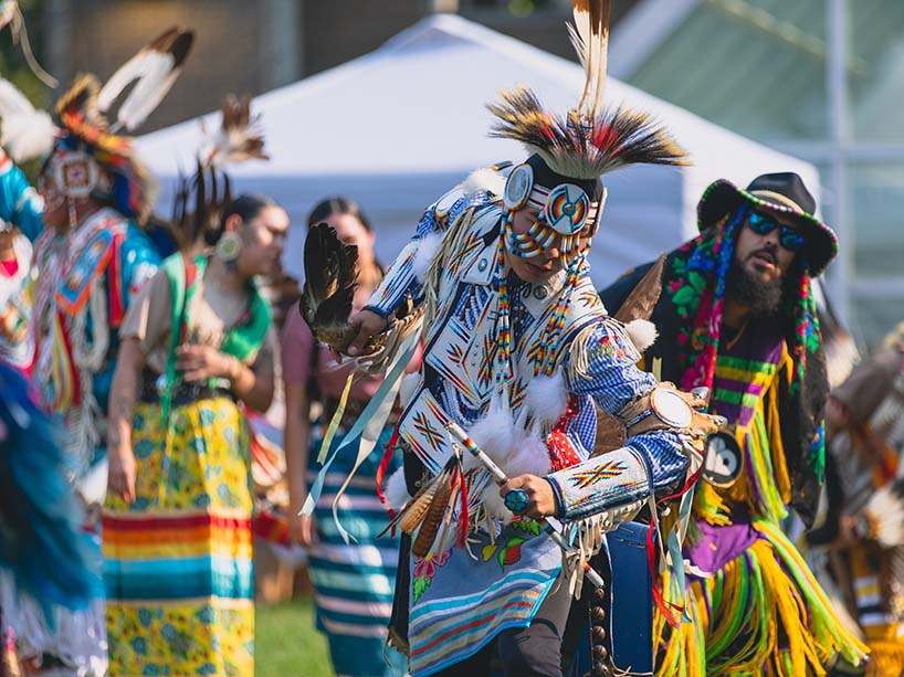 Wearing white regalia adorned with brightly coloured beads, Kirby Buffalo, head dancer takes to the Pow Wow circle.