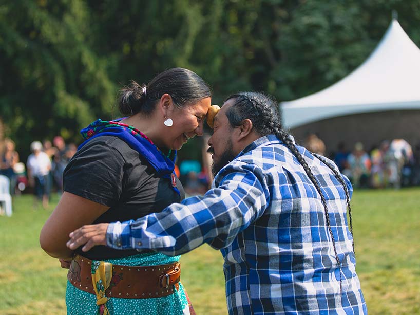 The winning couple of the potato dance balance the potato between their foreheads as they laugh and smile together.