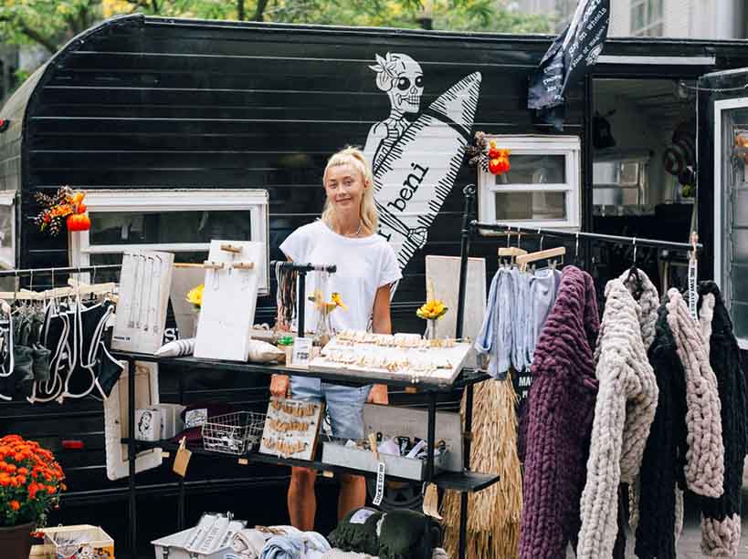 A young woman poses for a photo with a display of clothing and accessories.