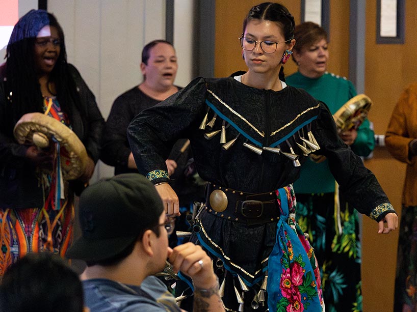 Alecea Yerxa dances at the celebration wearing a jingle dress. The Spirit Wind drum group sings in the background.