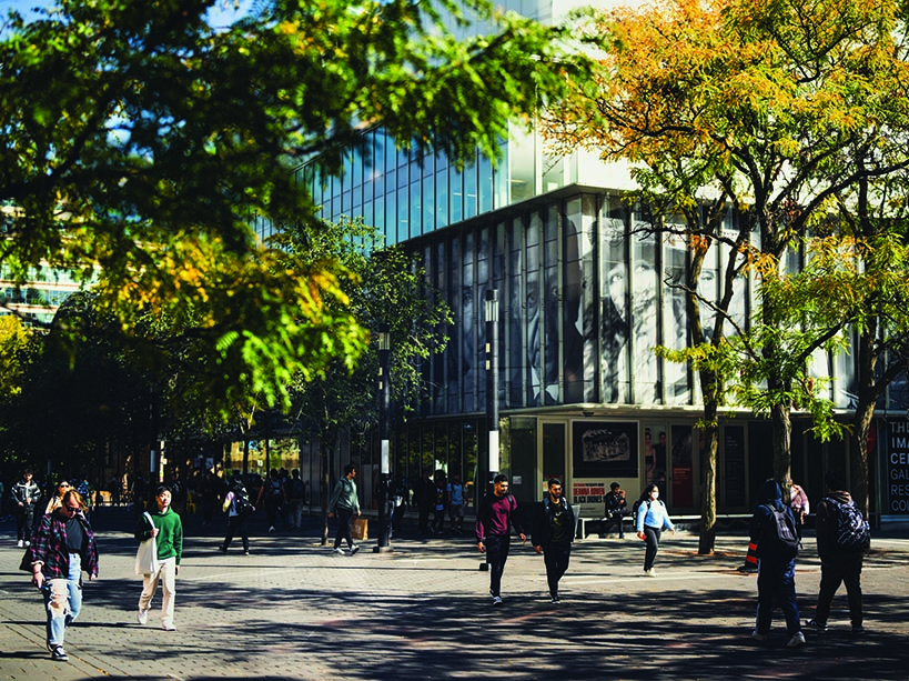 Students walk on Gould Street amid trees in fall colour