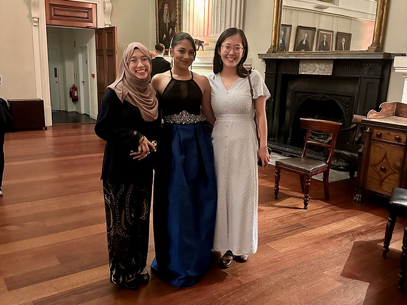 Anjali Singh, Haajar Binte Arman and Nan Sophia Han standing in front of a white pillar and fireplace at the GUA gala in Dublin.