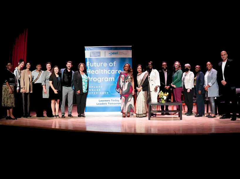 Members of the Future of Healthcare panel and team stand next to a sign for the program.