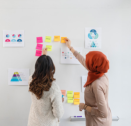 Two peers collaborating through sticky notes on a blank wall 