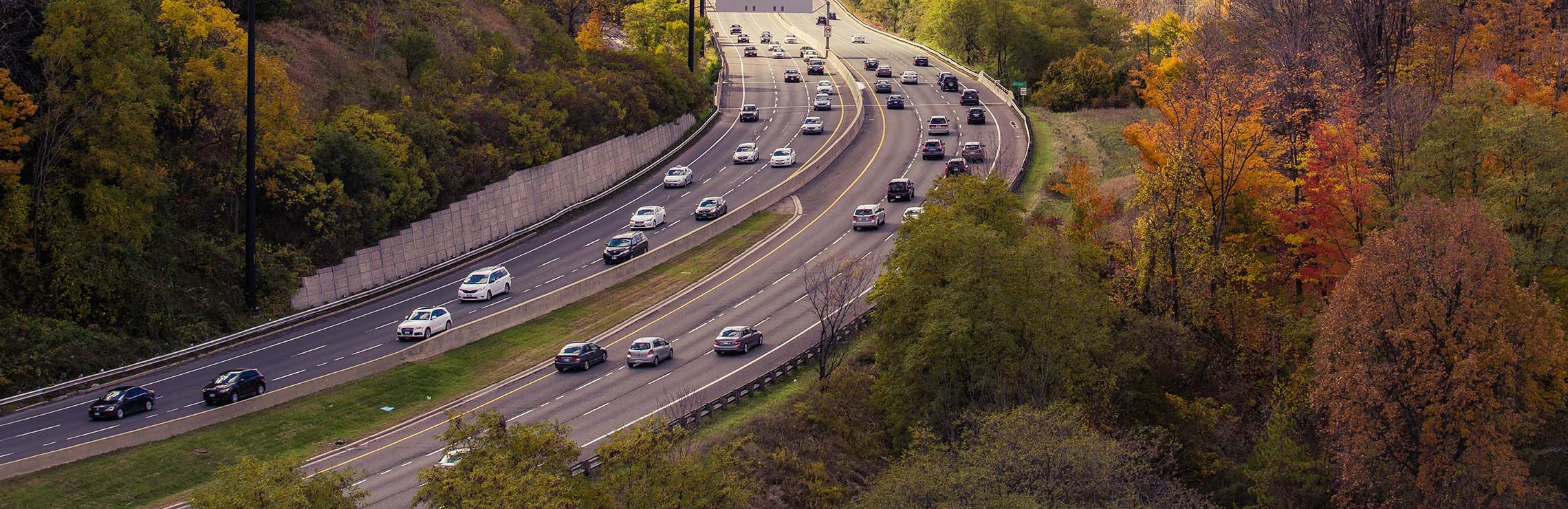 Flowing traffic on one to Toronto's highways, warm fall foliage 