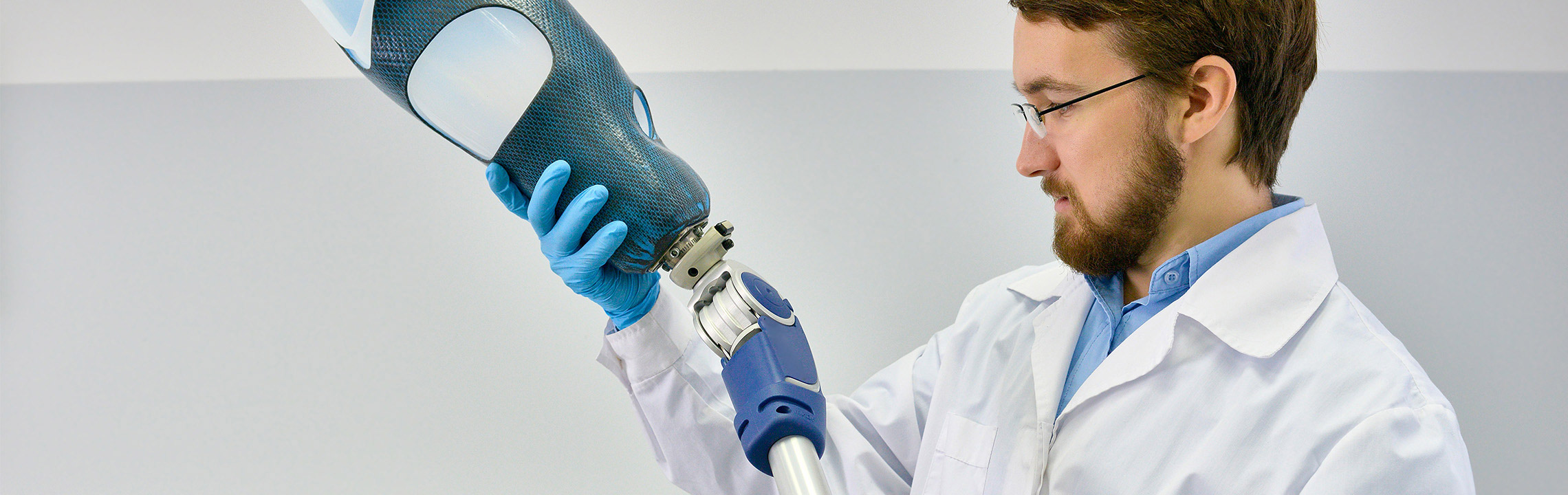 A Biomedical Engineering student in a lab coat inspects a prosthetic leg.