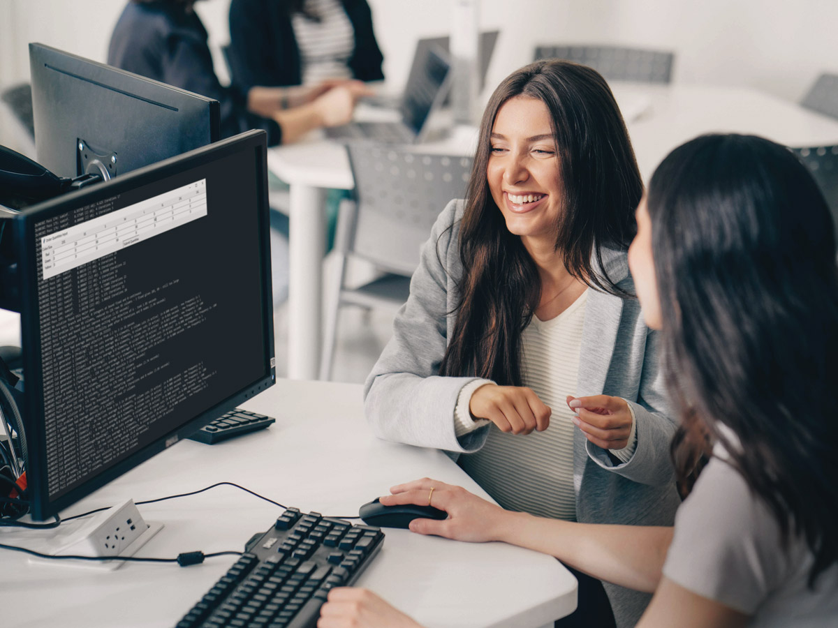 Two Industrial Engineering students laugh while working together in a computer lab.