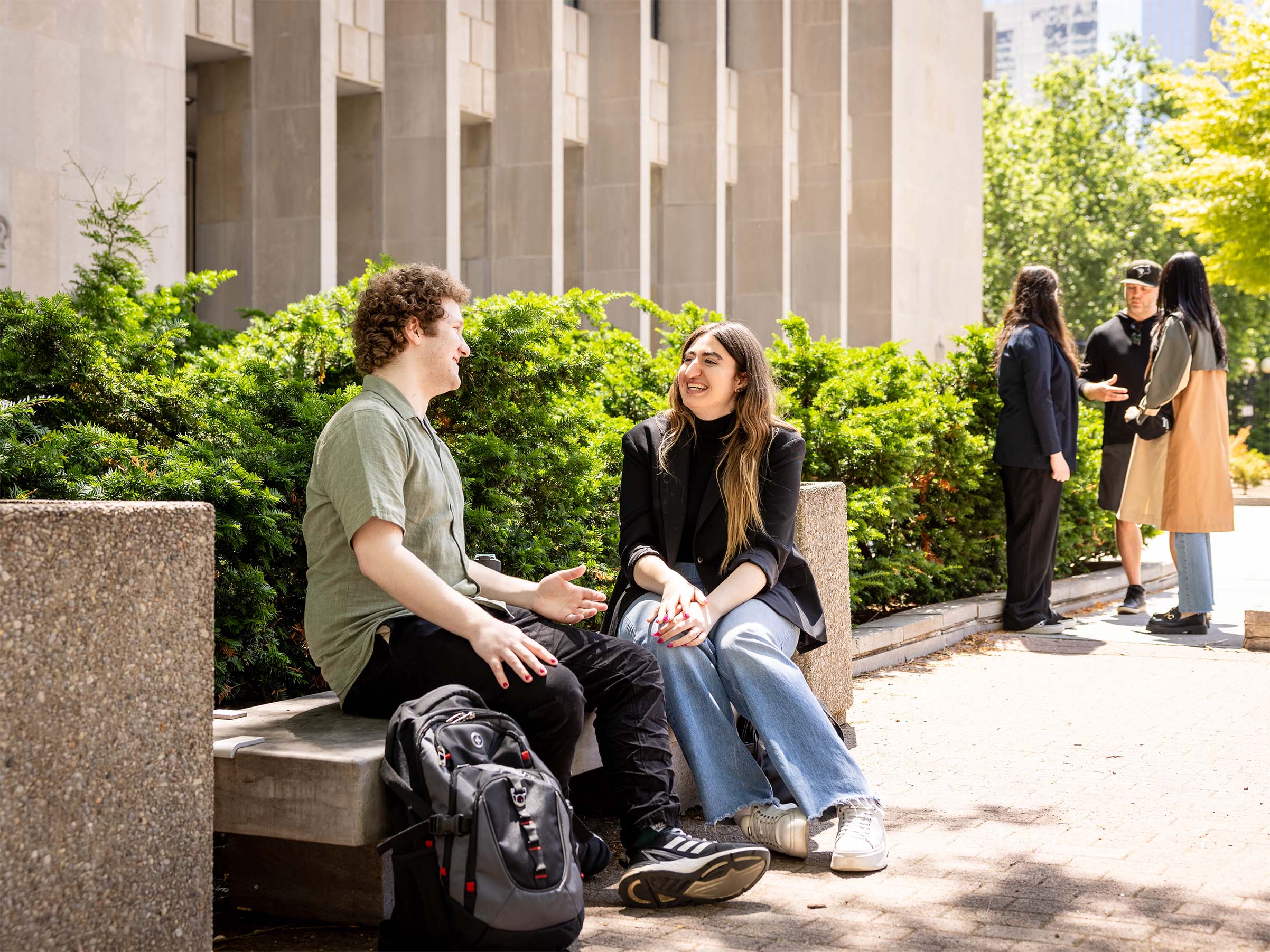 Two students chatting on a bench in front of the courthouse.