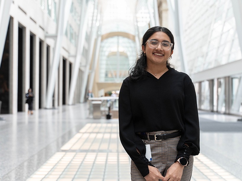 Sadia Billoo standing with a smile inside a building in the financial district.