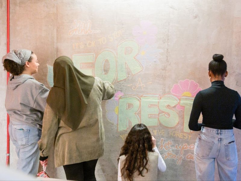 Students drawing chalk murals on the walls of SLC.