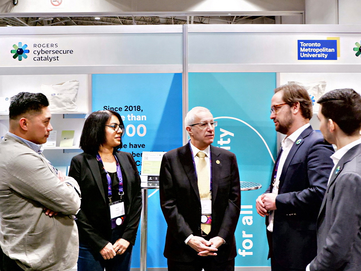 Ontario’s Minister of Economic Development, Job Creation and Trade Victor Fedeli speaks to representatives from TMU’s Rogers Cybersecure Catalyst at their conference booth. Photo credit: Christine Park/Rogers Cybersecure Catalyst.