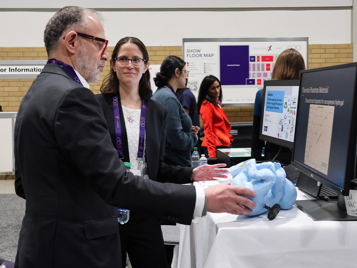 Steven N. Liss examines a blue silicone baby developed by professor Dafna Sussman to improve MR imaging techniques at the conference. Photo credit: Zeeanna Ibrahim/Zone Learning at Toronto Metropolitan University