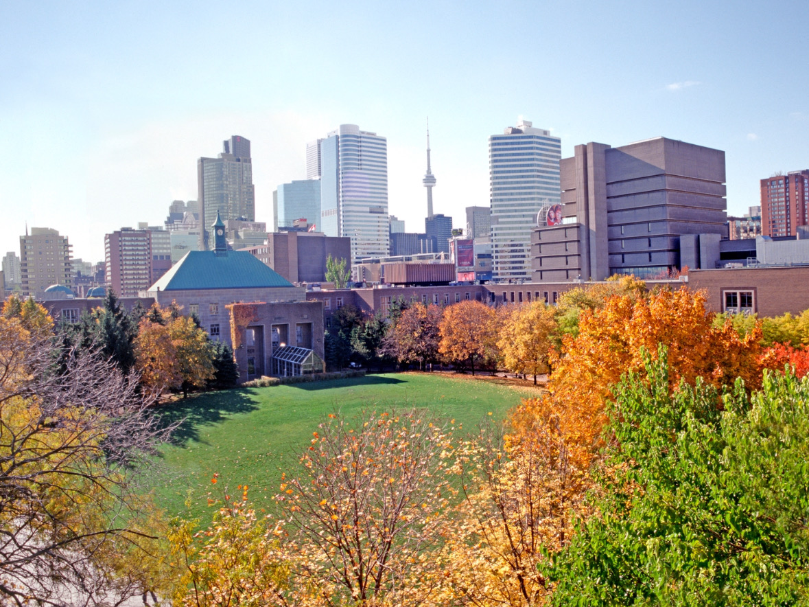 A mix of orange, yellow and green trees around the grass, surrounded by the Kerr Hall quad building. 