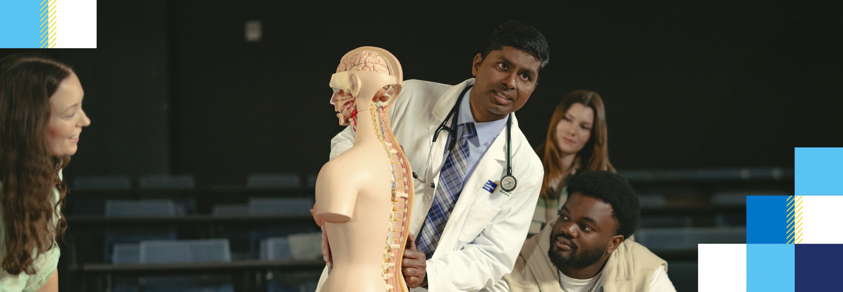 A male physician teaches a group of students using an anatomy model