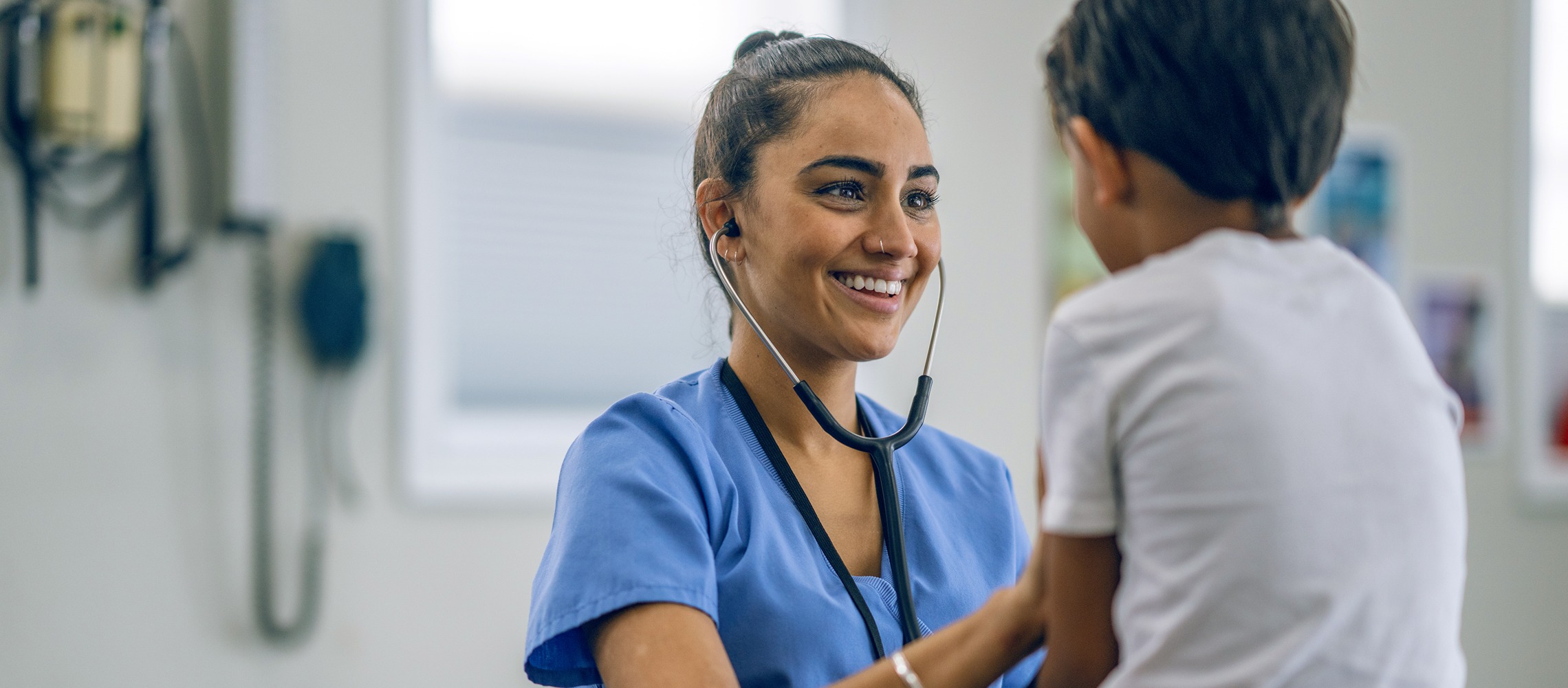 A South Asian female doctor does a checkup on a young patient in a doctor's office