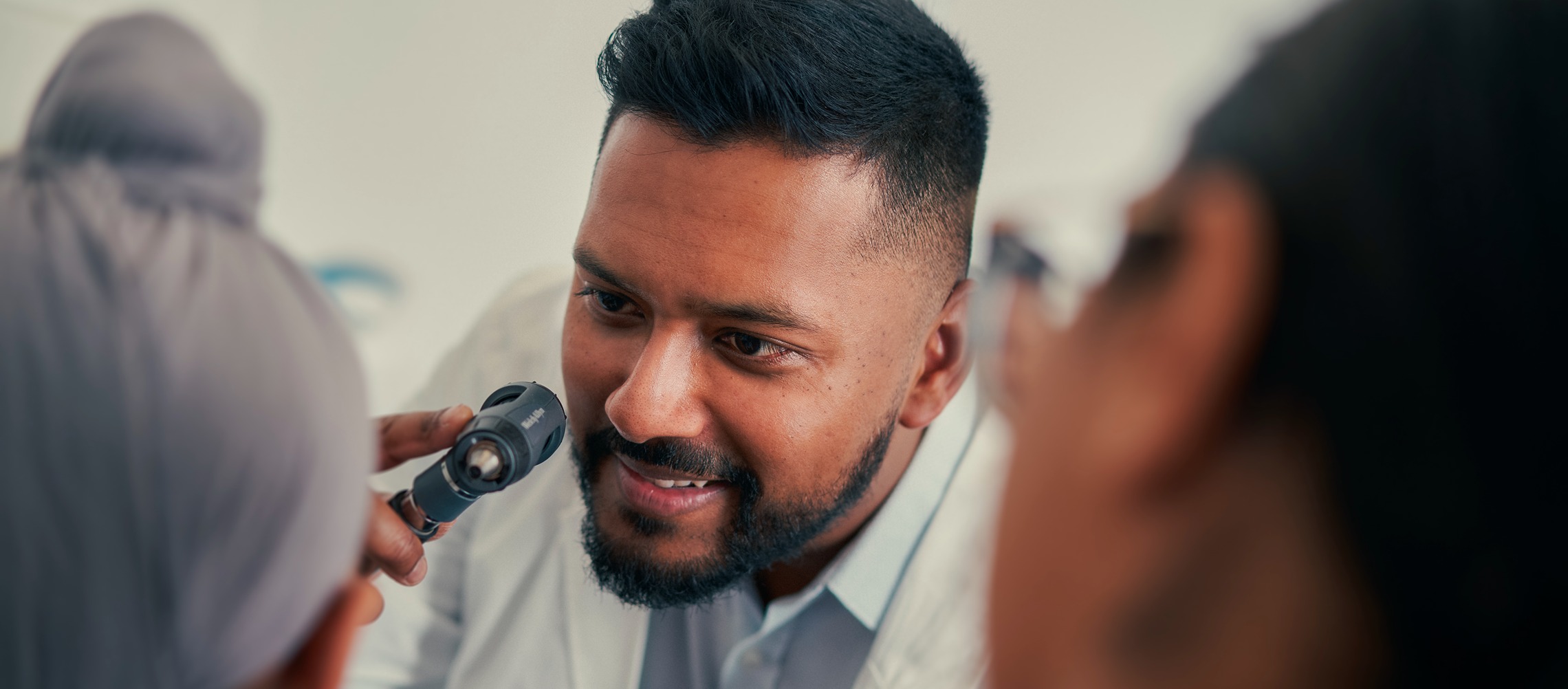 A South Asian male doctor performs a checkup on a young male patient