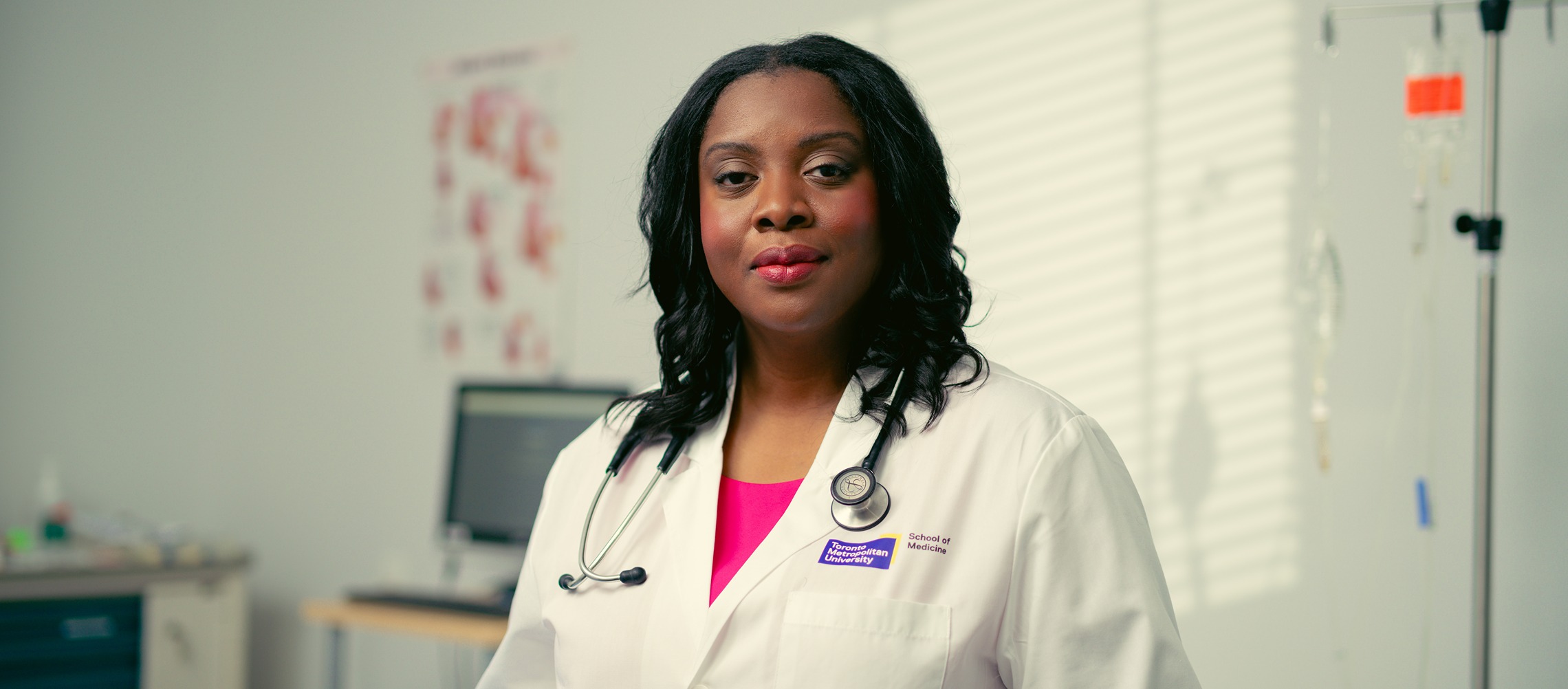 A Black female doctor stands in a hospital room