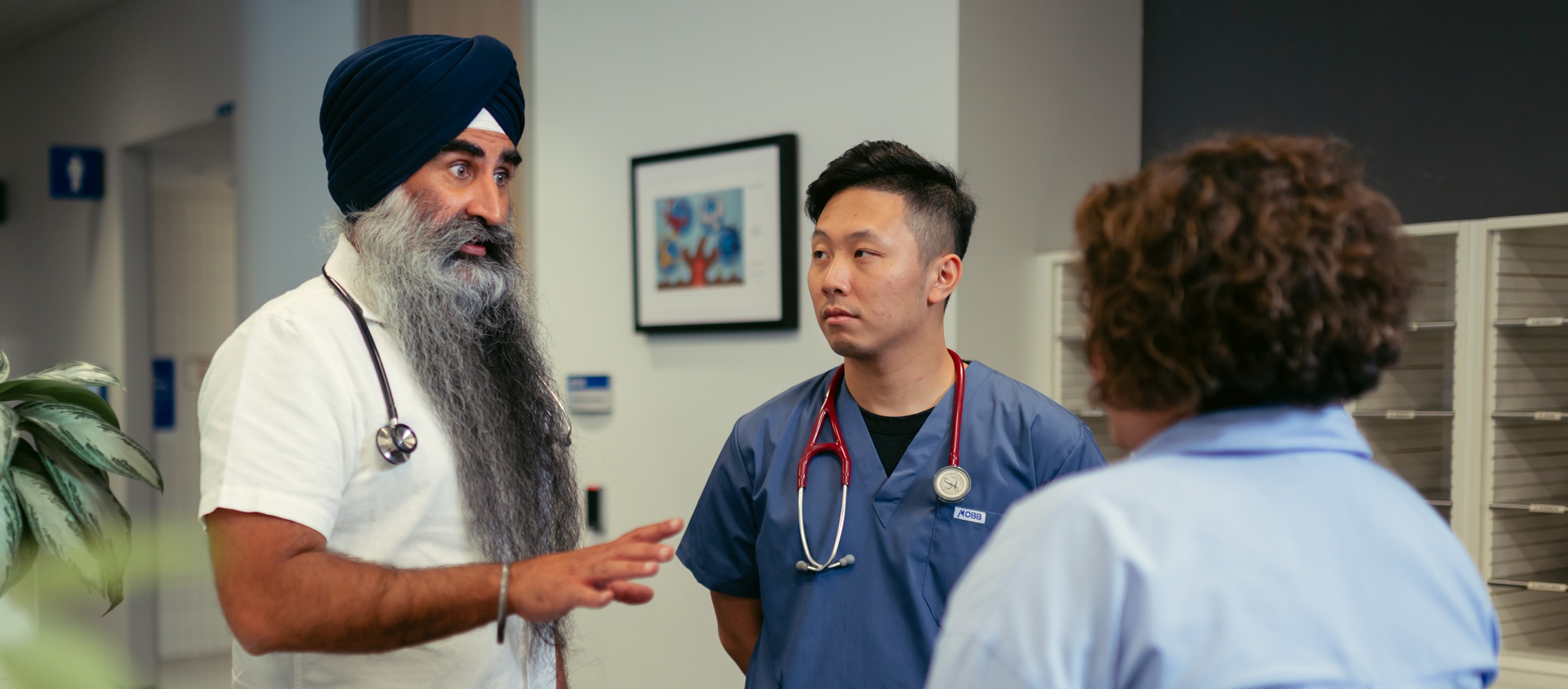 A male Sikh doctor speaks to a patient and resident