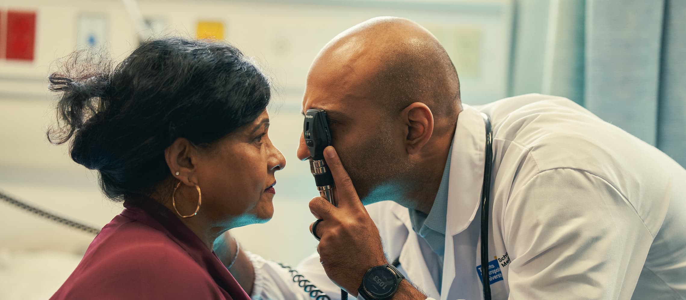 An optometrist examining the eye of an elderly woman using medical equipment
