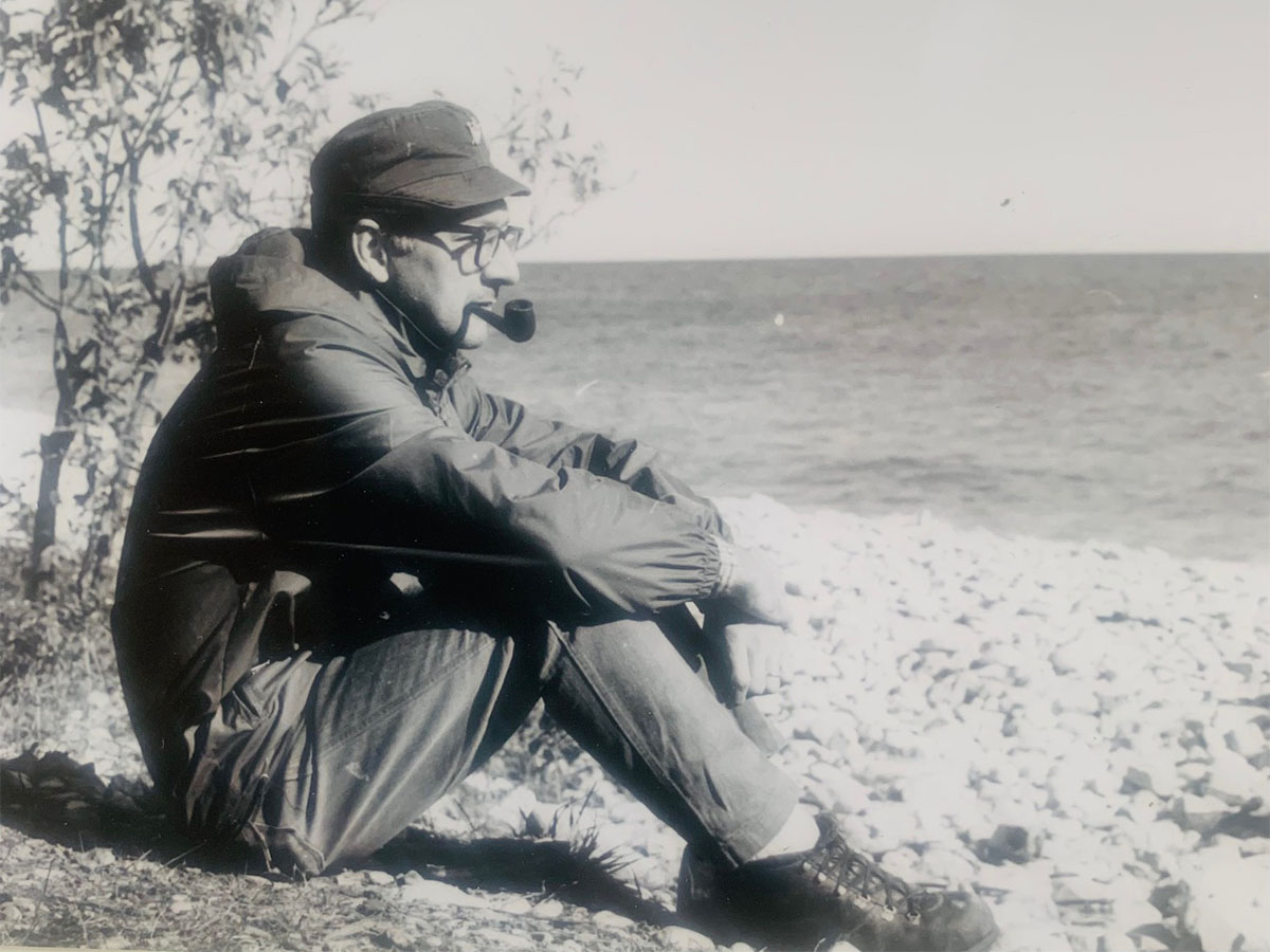 Young Fern Noel sitting by the shore with a cigar in his mouth