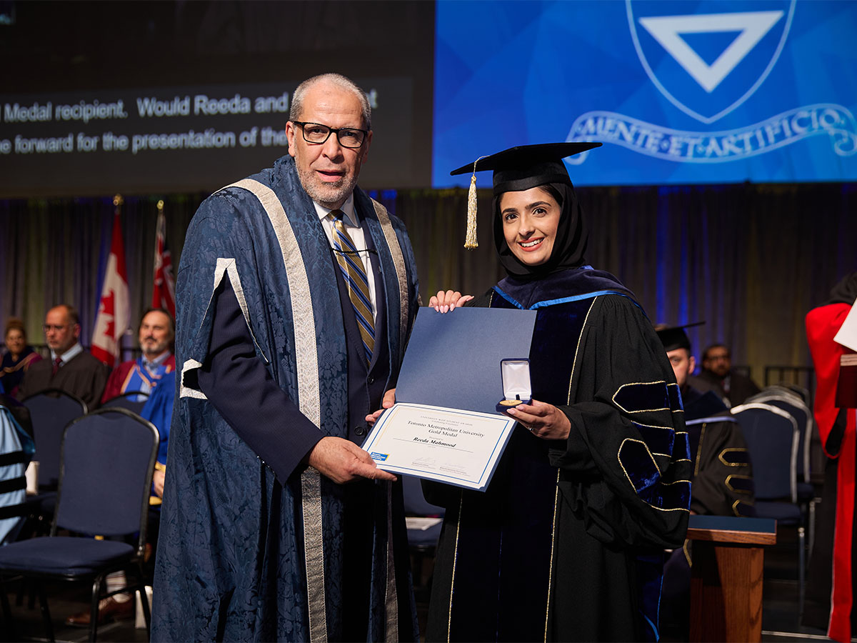 Reeda Mahmood accepting her gold medal at convocation beside President Lachemi