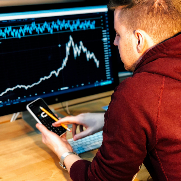 Man looking at desktop monitor and phone showing statistics