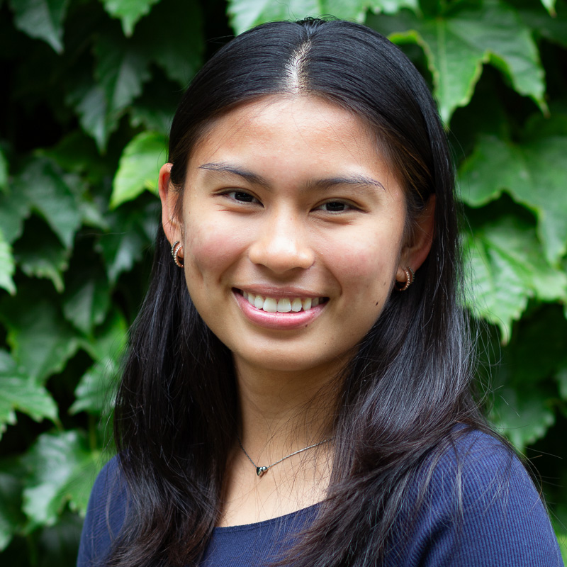 headshot of Althea Pioquinot, with long black hair, smiling, wearing navy shirt