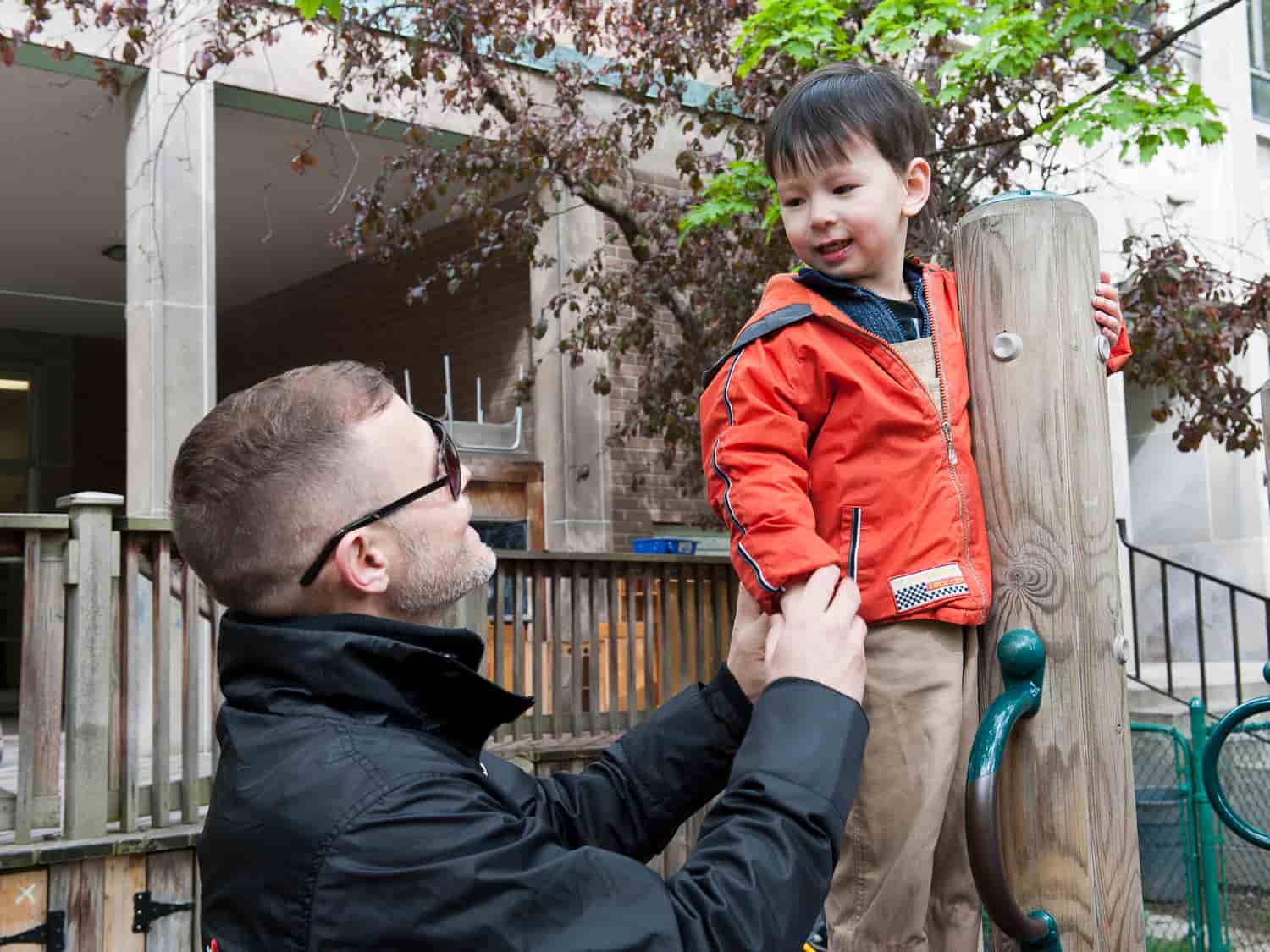 A man assists a child on a playground, fostering a supportive and engaging environment for play and learning.