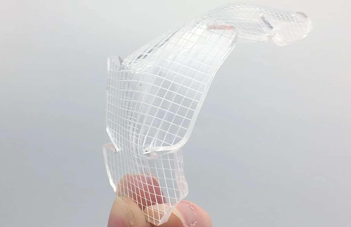 Fingers holding a small acrylic prototype of a design - IRD 400