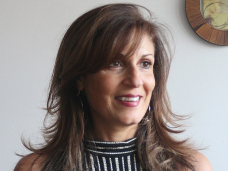 Samantha Wehbi wearing a striped shirt, smiling, with head tilted to the right. 