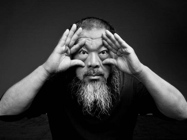 Black and white portraiit of Ai Weiwei with his hands opening his eyes.