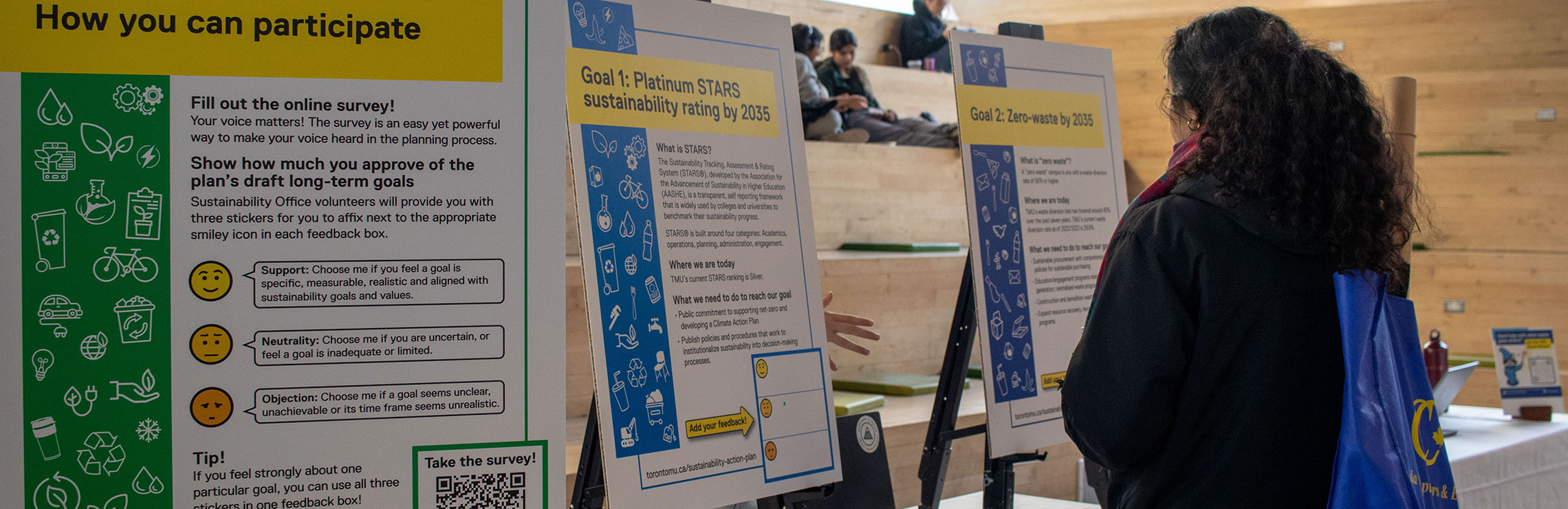 A student pauses to read a display at the Sustainability Expo in the SLC lobby.