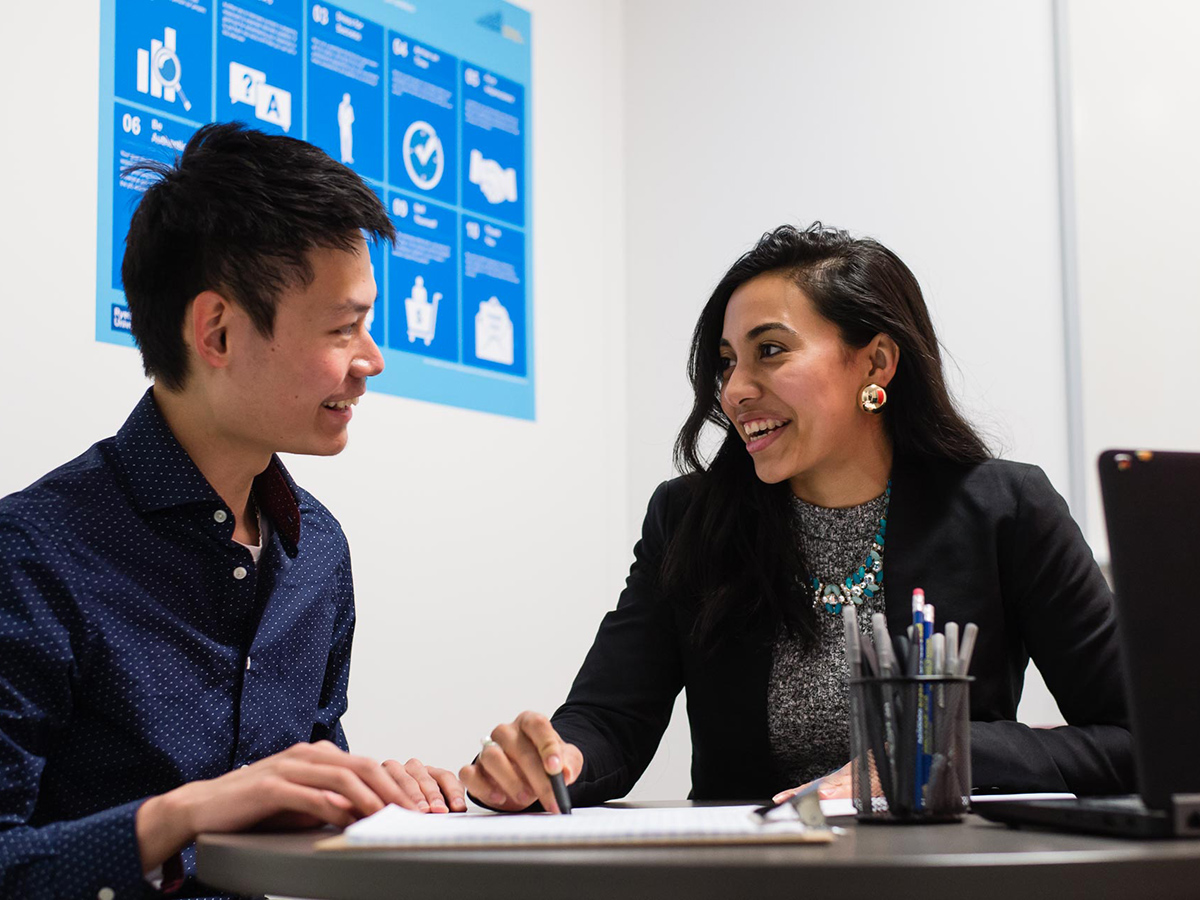 Two people sitting down having a discussion while smiling.