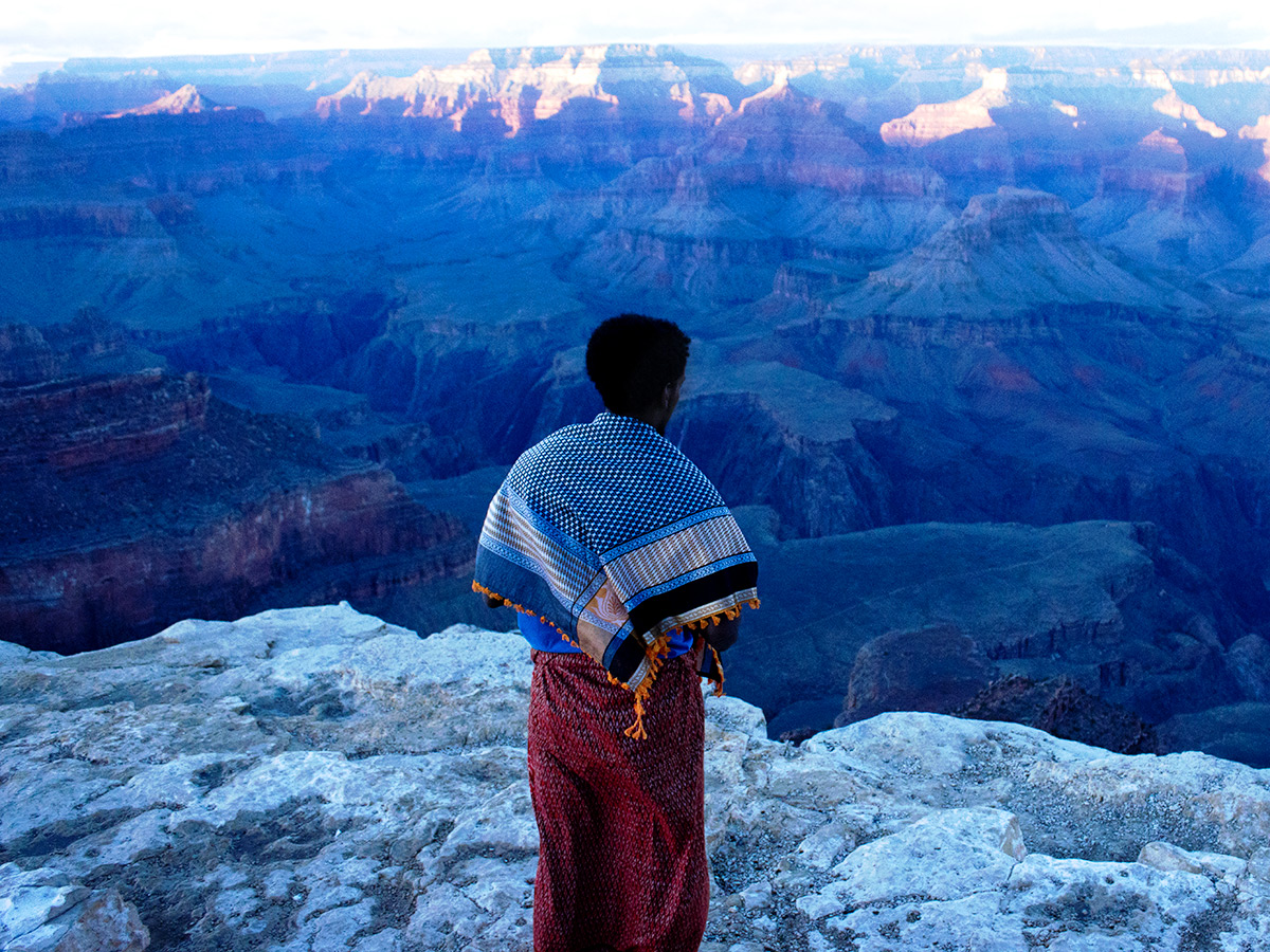 Photo by Aysha Ada of a male with panorama view of a mountain cliff