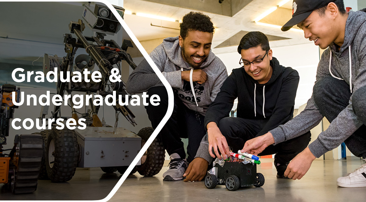 Three males students play with a robot with wheels in the SLC building