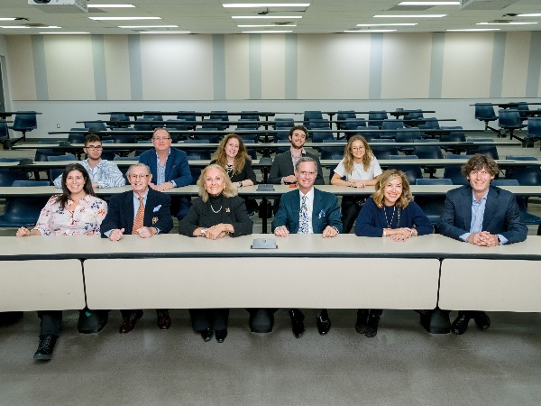 11 people sit in two rows within a Ted Rogers School of Management class room 